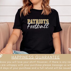 May include: A black t-shirt with the words "PATRIOTS Football" in gold lettering. The shirt is being worn by a person sitting on a pink sofa. The text "HAPPINESS GUARANTEE" is at the bottom of the image. The text below the guarantee reads: "We know you will love your shirt! However, if there is any reason you are unhappy with your purchase please message us within 14 days of your purchase and a full refund will be issued."