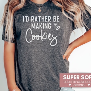 May include: A gray t-shirt with the text "I'd rather be making cookies" in white lettering. The shirt is super soft and available in multiple colors.