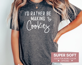 May include: A gray t-shirt with the text "I'd rather be making cookies" in white lettering. The shirt is super soft and available in multiple colors.