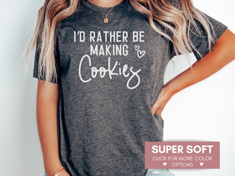 May include: A gray t-shirt with the text "I'd rather be making cookies" in white lettering. The shirt is super soft and available in multiple colors.