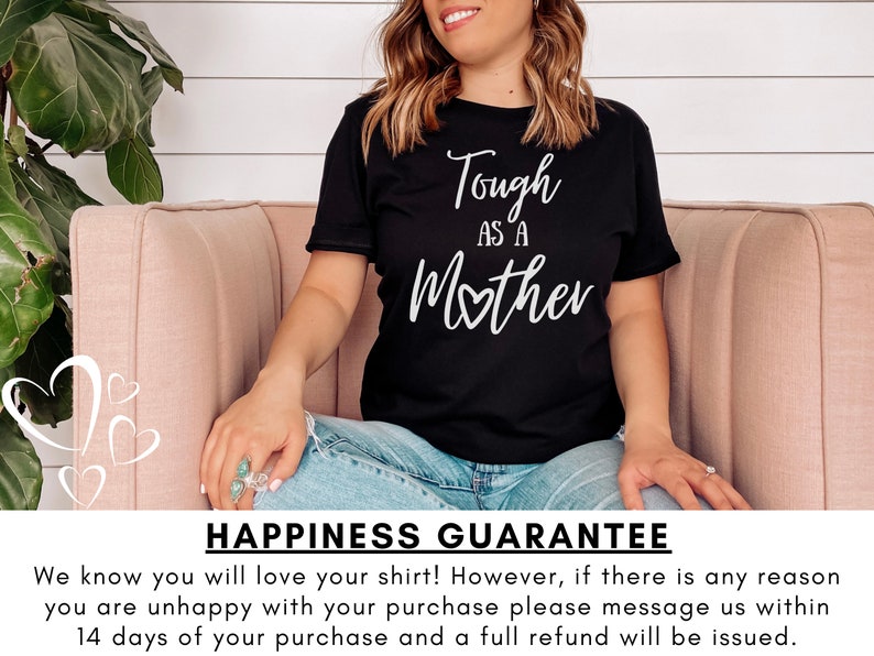 K&ouml;nnte beinhalten: Ein schwarzes T-Shirt mit wei&szlig;em Text, der "Tough as a Mother" lautet, wobei ein kleines Herz das "o" in Mother ersetzt. Das Shirt wird von einer Person getragen, die auf einem rosa Sofa sitzt. Der Text "Happiness Guarantee" befindet sich am unteren Rand des Bildes. Wir wissen, dass Sie Ihr Shirt lieben werden! Wenn Sie jedoch aus irgendeinem Grund mit Ihrem Kauf nicht zufrieden sind, kontaktieren Sie uns bitte innerhalb von 14 Tagen nach Ihrem Kauf, und wir erstatten Ihnen den vollen Kaufpreis.
