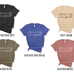 May include: Five different color t-shirts with the text "GROW YOUR own food" printed on the front. The colors are dark heather grey, soft cream, heather true royal, heather olive, and heather mauve.