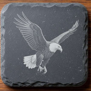 Op de afbeelding: Een vierkante onderzetter van donkergrijze leisteen met een lasergegraveerde witte afbeelding van een Amerikaanse zeearend in vlucht. De tekst DIGITAL DOWNLOAD, LASER ENGRAVING FILE, LIGHTBURN, XTOOL, CO2, NOXTEC by EnhanceVision en INSTANT DOWNLOAD is zichtbaar.