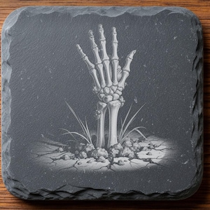 Könnte beinhalten: Ein quadratischer Untersetzer aus dunkelgrauem Schiefer mit einer Lasergravur einer skelettierten Hand, die aus rissiger Erde mit Grashalmen hervorkommt. Der Text oben lautet DIGITAL DOWNLOAD LASER ENGRAVING FILE LIGHTBURN XTOOL CO2 und NOXTEC unten.