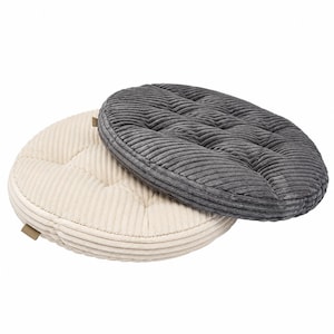 Pode incluir: Dois almofadas de assento redondas com tecido de veludo cotelê texturizado. Uma almofada é de cor creme e a outra é cinza escuro. Ambas as almofadas têm um design capitonê com padrões de costura visíveis e uma pequena aba de tecido na borda.