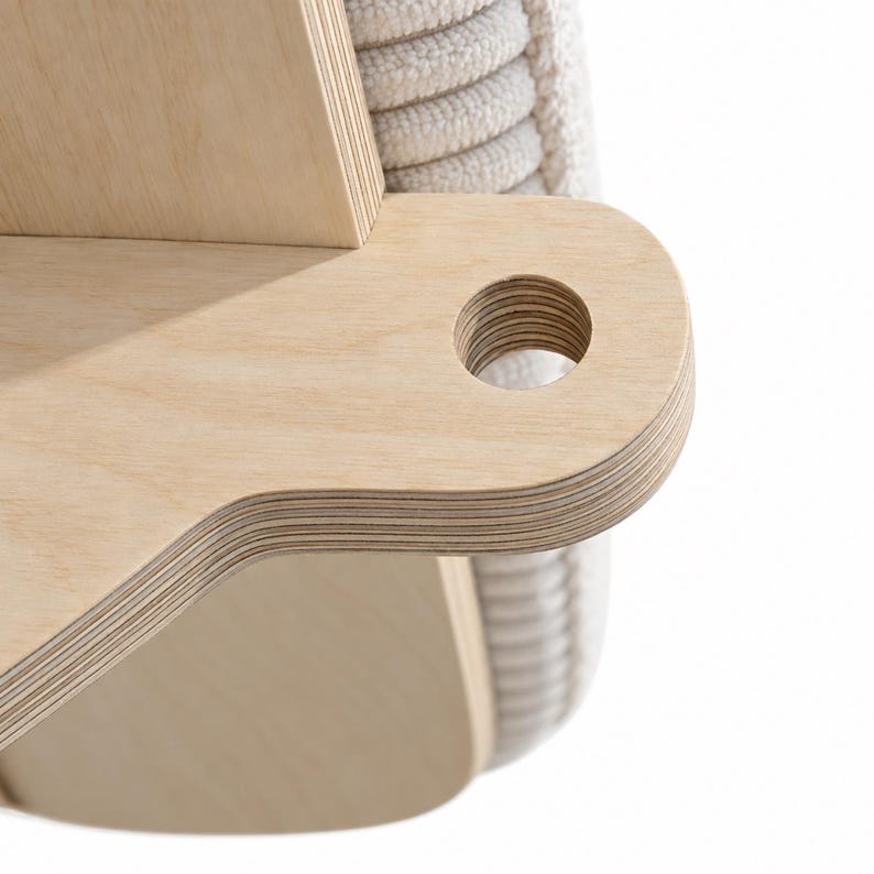 May include: A light-colored plywood furniture component featuring a smooth, layered wood grain edge and a circular cutout. The piece is attached to a section of off-white, vertically ribbed fabric upholstery, showing a clean, structural design.