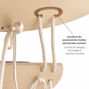 May include: A light-colored wooden platform with beige rope attachments and cutouts for hanging the bridge or hammock connect. The structure features layered plywood edges and a gray fabric surface visible on the lower section.