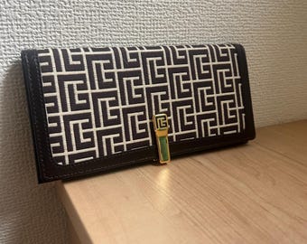 Cartera larga plegable con monograma de Pierre Balmain, confeccionada en tela y piel, con cierre de clip.