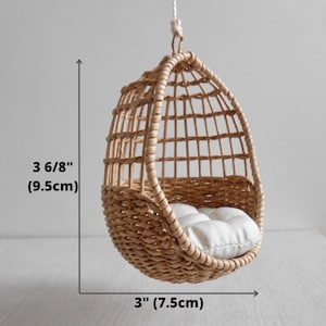 May include: A small, brown wicker hanging chair with a white cushion. The chair is 3 6/8 inches tall and 3 inches wide.