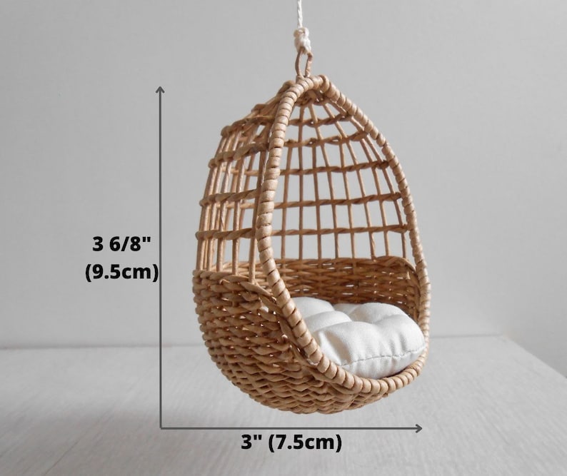 May include: A small, brown wicker hanging chair with a white cushion. The chair is 3 6/8 inches tall and 3 inches wide.