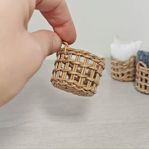以下が含まれることがあります： 取っ手付きの小さな籐製のバスケットが3つ。 バスケットは自然素材で作られており、薄い茶色をしています。