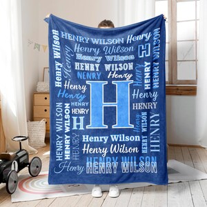Peut inclure: Une couverture bleu marine personnalisée avec le nom "Henry Wilson" en blanc et bleu clair. La couverture présente une grande lettre "H" au centre et est tenue par une personne.