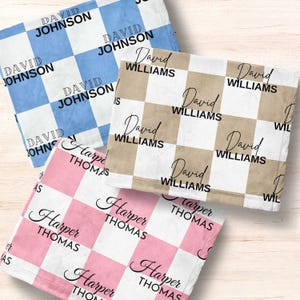May include: Three personalized baby blankets with a checkered pattern. The blankets are in blue, pink, and brown. The names "David Johnson", "David Williams", and "Harper Thomas" are printed on the blankets.