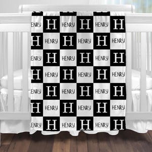 Peut inclure: Une couverture de bébé à carreaux noirs et blancs avec le nom "HENRY" et la lettre "H" répétée partout.