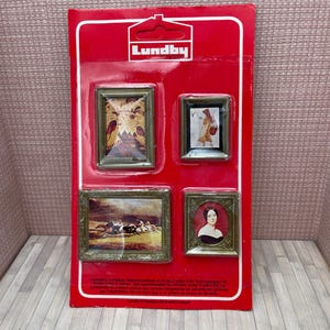 Peut inclure: Un ensemble de quatre tableaux miniatures encadrés sur une carte rouge Lundby. Les cadres dorés contiennent diverses images, dont un portrait, un paysage avec des chevaux et un motif abstrait.