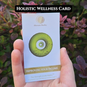 May include: A white card with the text "HOLISTIC WELLNESS CARD" at the top. The card features a green circular design with a white center and the words "IMPROVING YOUR INCOME" at the bottom. The card is held in a hand.