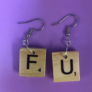 Peut inclure: Une paire de boucles d'oreilles en forme de tuiles de Scrabble en bois. Les tuiles épellent "FU" avec la lettre "F" ayant une valeur de 4 points et la lettre "U" ayant une valeur de 1 point.