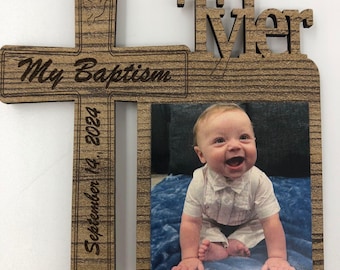 Puede incluir: Marco de fotos de bautizo de madera con el nombre "Tyler" recortado en la parte superior. El marco tiene forma de cruz e incluye el texto "My Baptism September 14, 2024". Una foto de un bebé está en el marco.