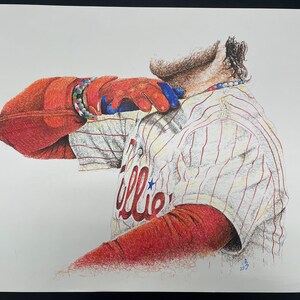 May include: A detailed pencil drawing of a baseball player wearing a white and red striped jersey with the word "Phillies" on the front. The player is wearing a red glove and has a red, white, and blue bracelet on their wrist.