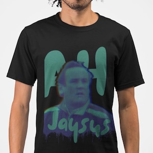 May include: Black t-shirt with a green and blue graphic print of a man's face with the text "AH Jaysus" underneath.