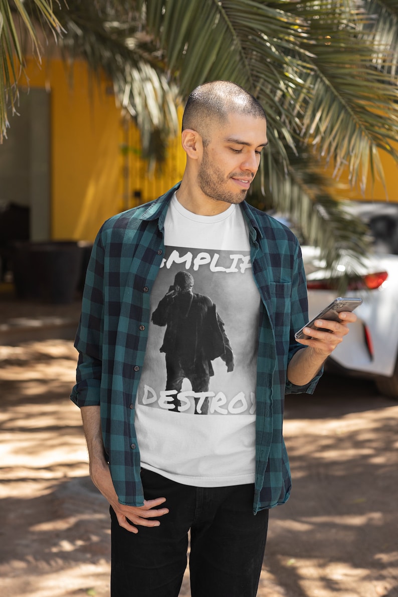 May include: A white t-shirt with a black and white graphic of a person with the text "Amplify Destroy" printed on the front.