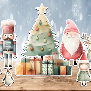 May include: A watercolor illustration of a Christmas scene with a decorated Christmas tree, a nutcracker, Santa Claus, a reindeer, a penguin, and a girl. The tree is decorated with ornaments and presents. The nutcracker is wearing a blue uniform and a red hat. Santa Claus is wearing a red suit with white trim and a white beard. The reindeer is wearing a blue and white hat. The penguin is wearing a red hat. The girl is wearing a green dress and a red hat.