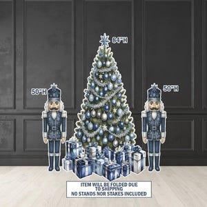 May include: A Christmas-themed display featuring a decorated Christmas tree (84"H) with blue ornaments, two nutcracker figures (50"H), and wrapped gift boxes. The tree is adorned with silver garland and star-shaped ornaments. The nutcrackers are in blue uniforms.