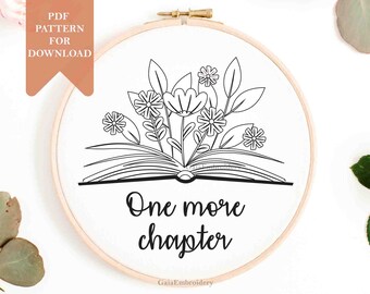 May include: An embroidery hoop featuring a black and white floral design sprouting from an open book. The text "One more chapter" is below the book. The words "PDF pattern for download" are in the upper left corner.