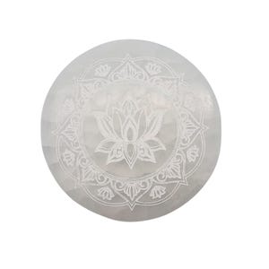 Può includere: Una piastra rotonda di cristallo di selenite bianca con un disegno di fiore di loto inciso al centro. Il loto è circondato da un intricato motivo floreale. La piastra è liscia e ha un aspetto naturale e traslucido.