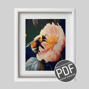 Peut inclure: Modèle de point de croix en PDF à télécharger d'une abeille pollinisant une fleur rose avec un centre jaune. L'abeille est jaune et noire avec des ailes brunes. La fleur est entourée de feuilles vertes.