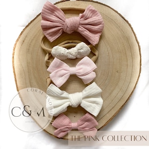 May include: Set of five pink and white fabric headbands with bows. The headbands are arranged on a wooden surface. The text "The Pink Collection" is visible at the bottom of the image.