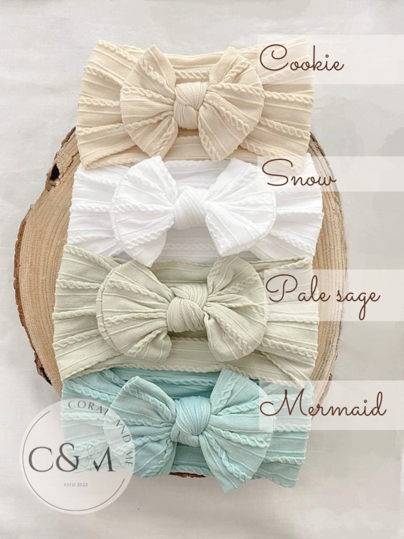 K&ouml;nnte beinhalten: Vier verschiedene farbige, gekn&uuml;pfte Stirnb&auml;nder, &uuml;bereinander gestapelt. Die Farben sind beige, wei&szlig;, hellgr&uuml;n und hellblau. Die Stirnb&auml;nder sind mit "Cookie", "Snow", "Pale sage" und "Mermaid" beschriftet.