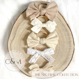 May include: Five different hair bows in neutral colors on a wooden surface. The bows are made of different materials, including lace, fabric, and ribbon. The text "THE NEUTRAL COLLECTION" is visible at the bottom of the image.