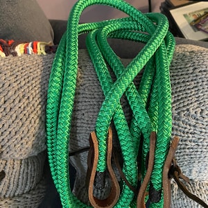 May include: Green braided rope with brown leather handles. The rope is coiled and the handles are visible.