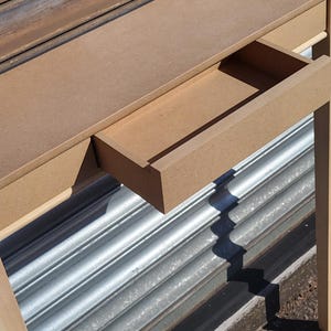 May include: A light brown console table constructed from unfinished medium-density fiberboard. The table features a flat rectangular top surface and a single pull-out drawer positioned centrally beneath the top, showcasing a smooth, matte texture.
