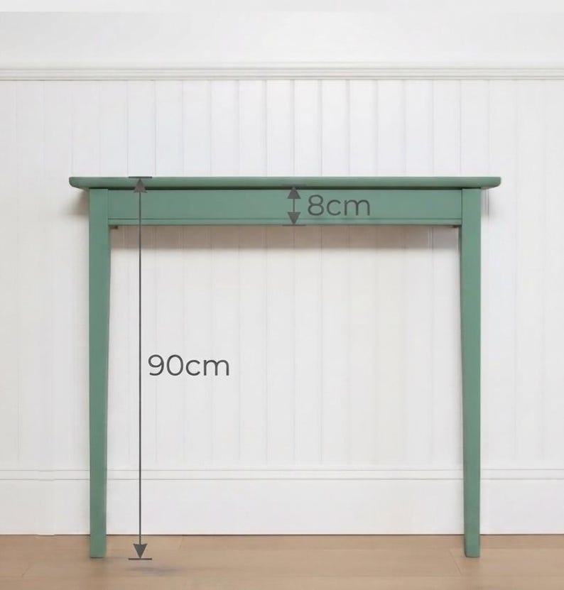 May include: A sage green console table with a rectangular top and four straight legs. The table features a visible measurement of 8 cm for the apron height and 90 cm for the total height from the floor to the top surface of the console table.