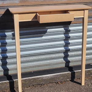 May include: A light tan wooden console table featuring a rectangular top and four straight legs. The table includes a single central drawer that is partially pulled out, revealing the interior compartment and the smooth, unfinished wood surface.