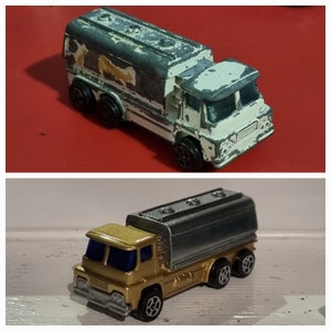 May include: Two toy tanker trucks, one is white with gray and brown paint and the other is gold with silver paint.