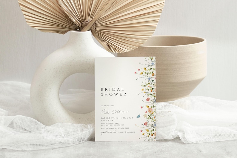 Puede incluir: Una tarjeta blanca con un borde floral y el texto "Bridal Shower" en negro. La tarjeta tambi&eacute;n incluye el texto "En honor a Laura Collins" y la fecha "S&aacute;bado, 11 de junio de 2023".