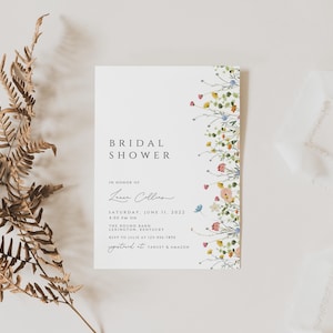 Puede incluir: Una invitaci&oacute;n de ducha nupcial blanca con un borde floral. La invitaci&oacute;n dice "Bridal Shower" en texto negro y "En honor de Laura Collins" en cursiva. La fecha es el s&aacute;bado 11 de junio de 2022 a las 4:00 PM. La ubicaci&oacute;n es The Round Barn, Lexington, Kentucky. RSVP a Julie al 123-456-7890. La invitaci&oacute;n est&aacute; decorada con un borde floral de acuarela.