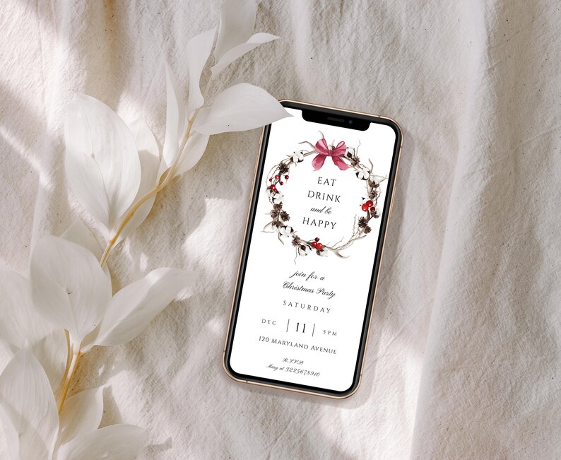 May include: A smartphone displaying a Christmas party invitation with a wreath of cotton bolls, berries, and a pink bow. The text reads "Eat Drink and be Happy", "Join for a Christmas Party", "Saturday", "Dec 11 5pm", "120 Maryland Avenue", and "May at 3225678910".