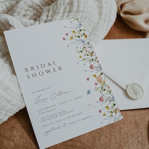 Puede incluir: Una tarjeta blanca con un borde floral y el texto "Bridal Shower" en negro. La tarjeta tambi&eacute;n incluye el texto "En honor de Laura Collins" en cursiva, "S&aacute;bado, 11 de junio de 2022" en negro, "4:00 PM on" en negro, "The Round Barn" en negro, "Lexington, Kentucky" en negro, "RSVP a Julie al 123-456-7890" en negro, y "Registered at Target & Amazon" en negro.