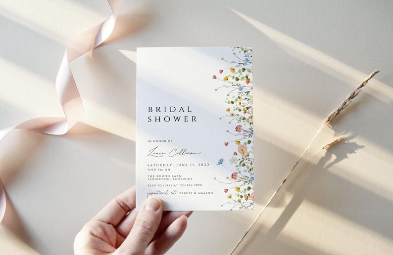 Puede incluir: Una invitaci&oacute;n de ducha nupcial blanca con un borde floral. La invitaci&oacute;n dice "Bridal Shower" en una fuente simple e incluye el nombre "Laura Collins" en cursiva. La fecha es el s&aacute;bado 11 de junio de 2022 a las 2:00 PM. La ubicaci&oacute;n es The Round Barn, Lexington, Kentucky. RSVP al [n&uacute;mero de tel&eacute;fono] antes del [fecha].