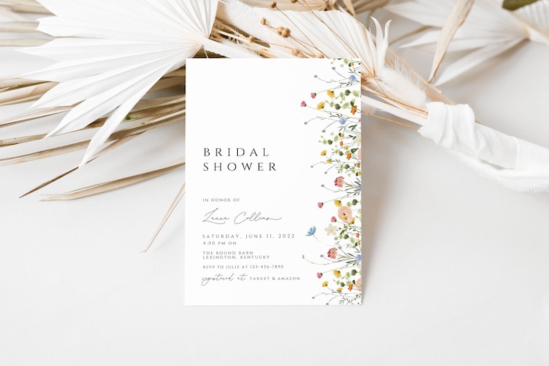 Puede incluir: Una invitaci&oacute;n de ducha nupcial blanca con un borde floral. El texto dice "Bridal Shower" en honor a "Laura Collins" el s&aacute;bado 11 de junio de 2022 a las 4:00 PM en The Round Barn, Lexington, Kentucky. RSVP a Julie al 123-456-7890. Registrado en Target & Amazon.