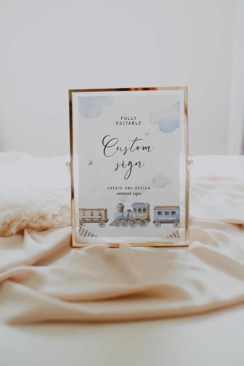 May include: A gold-framed sign with a white background and blue watercolor clouds. The text "FULLY EDITABLE Custom sign CREATE AND DESIGN unlimited signs" is printed on the sign. A blue and brown train with three cars is illustrated at the bottom of the sign.