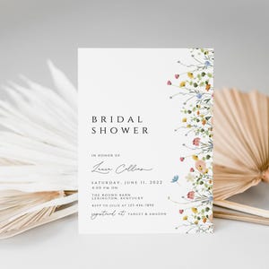 Puede incluir: Una invitaci&oacute;n de ducha nupcial blanca con un borde floral. La invitaci&oacute;n dice "Bridal Shower" en honor a "Laura Collins" e incluye la fecha, la hora, la ubicaci&oacute;n y la informaci&oacute;n de RSVP.
