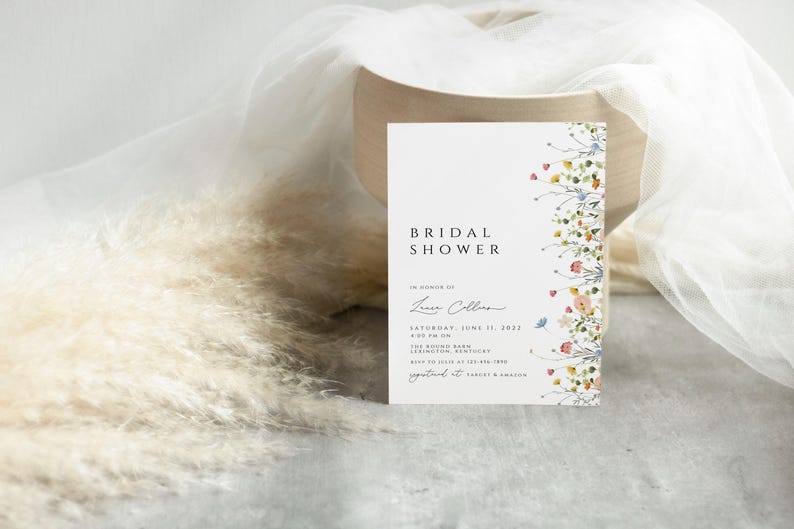 Puede incluir: Una invitaci&oacute;n de ducha nupcial blanca con un borde floral. La invitaci&oacute;n dice "Bridal Shower" en texto negro y "En honor a Laura Collins" en cursiva. La fecha es el s&aacute;bado 11 de junio de 2023.