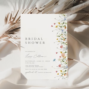 Puede incluir: Una tarjeta blanca con un borde floral y el texto "BRIDAL SHOWER" en negro. La tarjeta tambi&eacute;n incluye el texto "IN HONOR OF Leanne Collins" en cursiva negra. La tarjeta tambi&eacute;n incluye el texto "SATURDAY, JUNE 11, 2022 4:00 PM ON THE ROUND BARN LEXINGTON KENTUCKY RSVP TO JULIE AT 123-456-7890 REGISTERED AT TARGET & AMAZON" en negro.