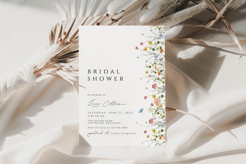 Puede incluir: Una tarjeta blanca con un borde floral y el texto "BRIDAL SHOWER" en negro. La tarjeta tambi&eacute;n incluye el texto "IN HONOR OF Leanne Collins" en cursiva negra. La tarjeta tambi&eacute;n incluye el texto "SATURDAY, JUNE 11, 2022 4:00 PM ON THE ROUND BARN LEXINGTON KENTUCKY RSVP TO JULIE AT 123-456-7890 REGISTERED AT TARGET & AMAZON" en negro.
