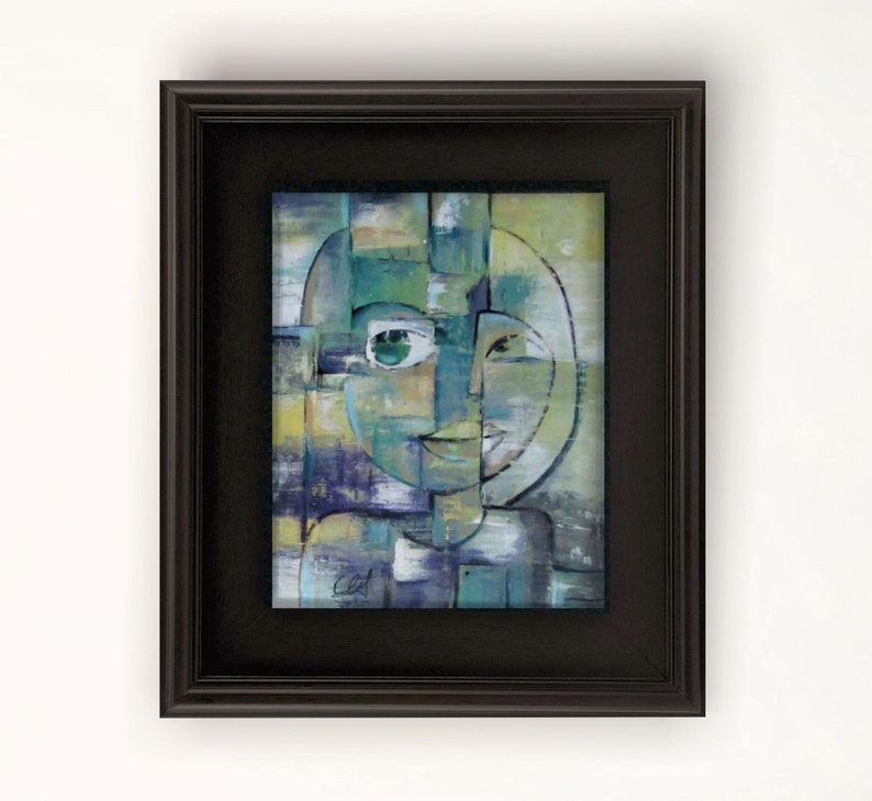 May include: Abstract painting of a face with green eyes and a smile, framed in a black frame.